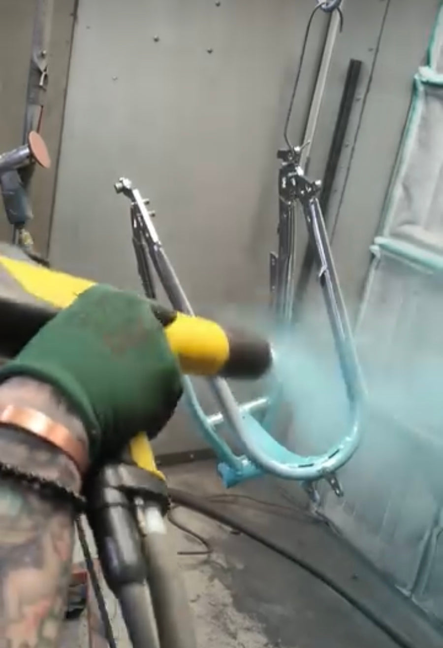 Powder being sprayed onto a frame in the booth