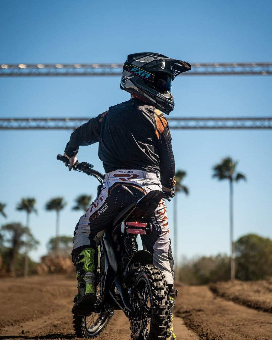 Rider on a Talaria X3 Mini seen from behind on a dirt track