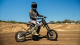 Rider seated on a Talaria X3 Mini — side view on a dirt track