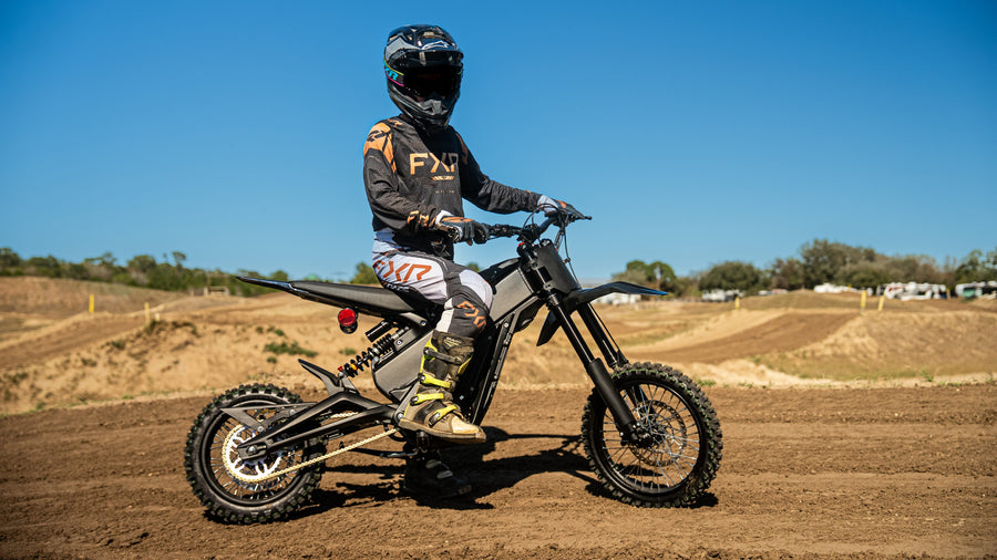 Rider seated on a Talaria X3 Mini — side view on a dirt track