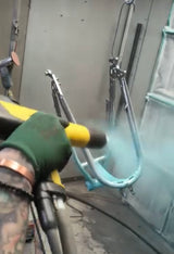 Powder being sprayed onto a frame in the booth