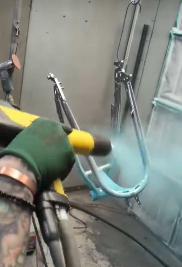 Powder being sprayed onto a frame in the booth
