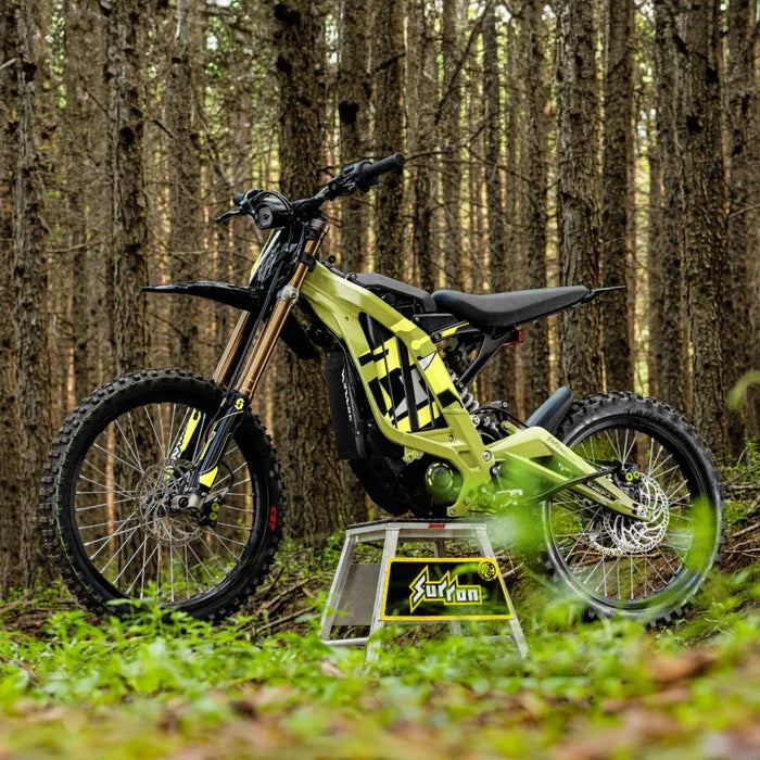 Sur-Ron Light Bee X in Green on a stand on a forest trail